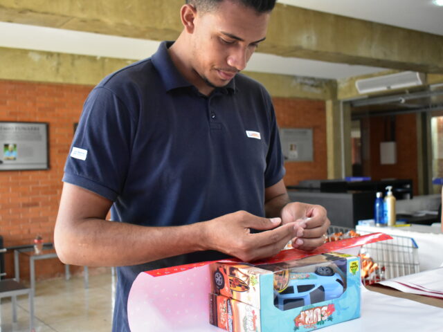 Colaborador embalando os presentes comprados pela Funarbe para posterior distribuição às creches