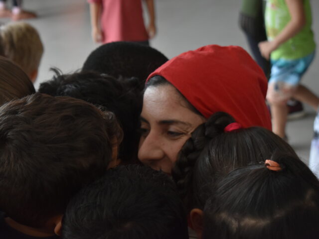 Colaboradora sendo abraçada por muitas crianças na Creche São Sebastião
