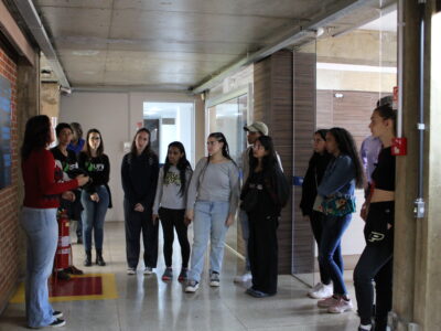 Estudantes ouvindo fala de colaboradora da Funarbe em um dos corredores do Edifício Sede.